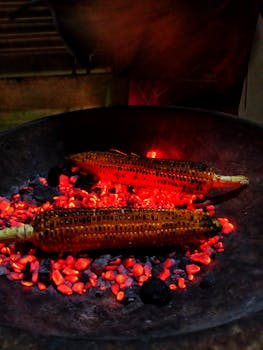 Close-up of corn cobs roasting over glowing coals, capturing the essence of street food delight.