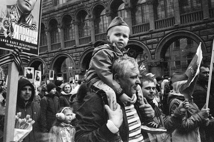 Little Boy Piggybacking On Mans Shoulders During Protest