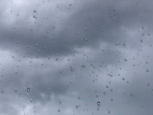 Free Raindrops on a window with a dramatic stormy sky in the background, capturing nature's unpredictability. Stock Photo