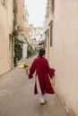 Woman in Red Long Sleeve Dress Holding Brown Woven Basket Walking on Street