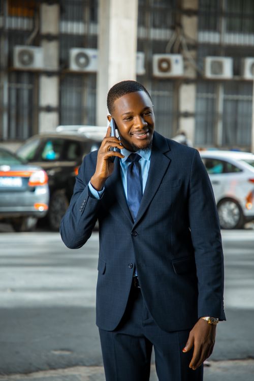 Free Confident businessman in suit talking on phone outdoors in Dakar, Senegal. Stock Photo