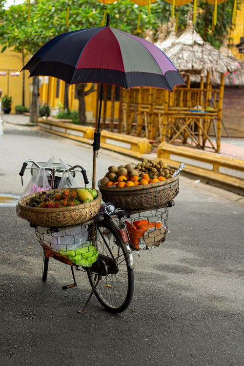 Free Bicycle with baskets of fruits under an umbrella on a street in Hoi An, Vietnam. Stock Photo