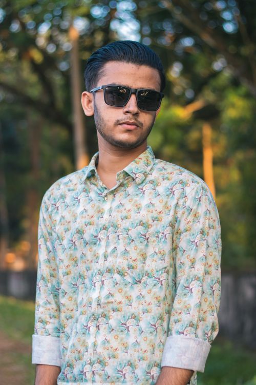 Free Young man in sunglasses and floral shirt posing outdoors on a sunny day. Stock Photo