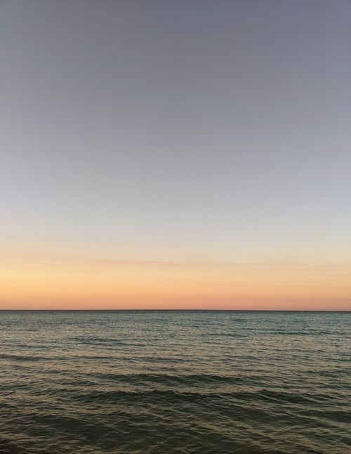 Free Peaceful ocean view at sunset with clear skies and gentle waves. Stock Photo