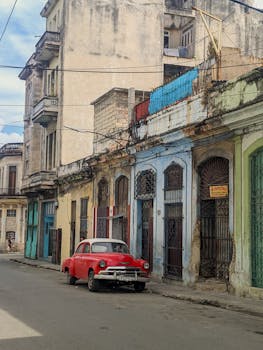 A classic red car parked along the colorful, weathered streets of Havana, Cuba.