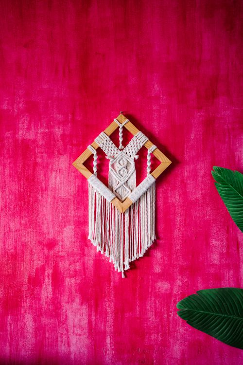 Free Handmade macrame art with wooden frame against a textured pink wall. Stock Photo