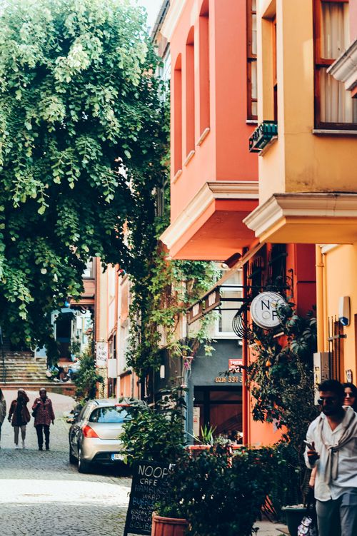 Free Vibrant street scene with colorful buildings and lush greenery in a sunny urban area. Stock Photo