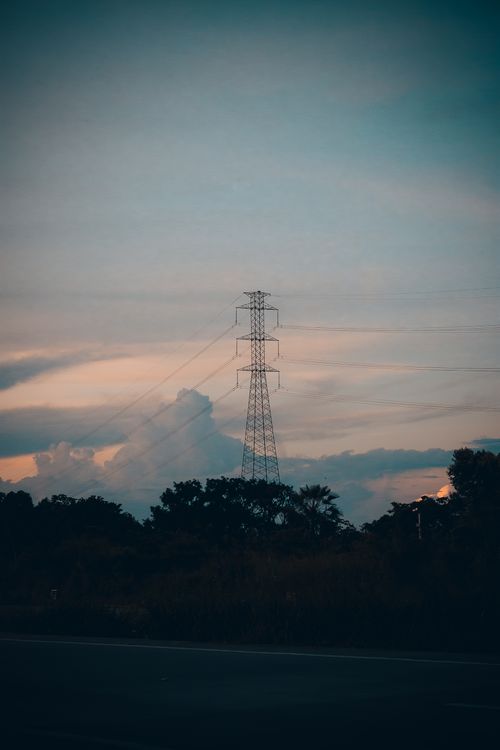 Free A dramatic sunset silhouettes a power line tower against a colorful sky in Maracanaú, Brazil. Stock Photo