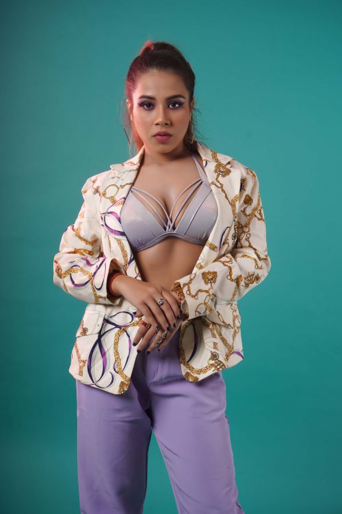 Free Fashionable woman in blazer and bra posing against teal background, showcasing modern style. Stock Photo