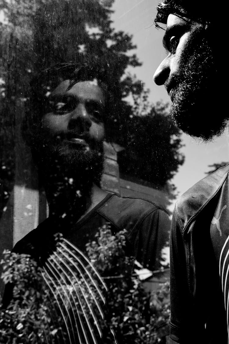 Grayscale Photo Of A Man Looking At A Glass