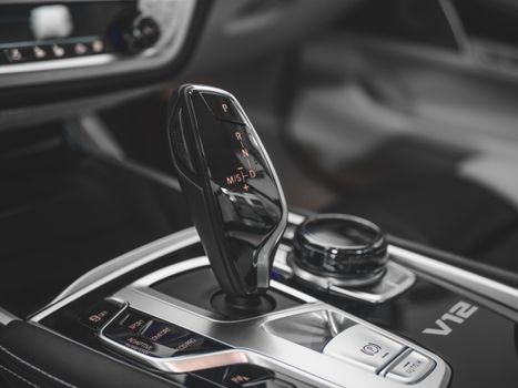 Close-up of a luxury car gearshift in a sleek, modern vehicle interior, highlighting advanced automotive technology.