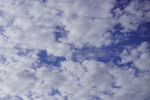 A tranquil view of white fluffy clouds scattered across a vivid blue sky.