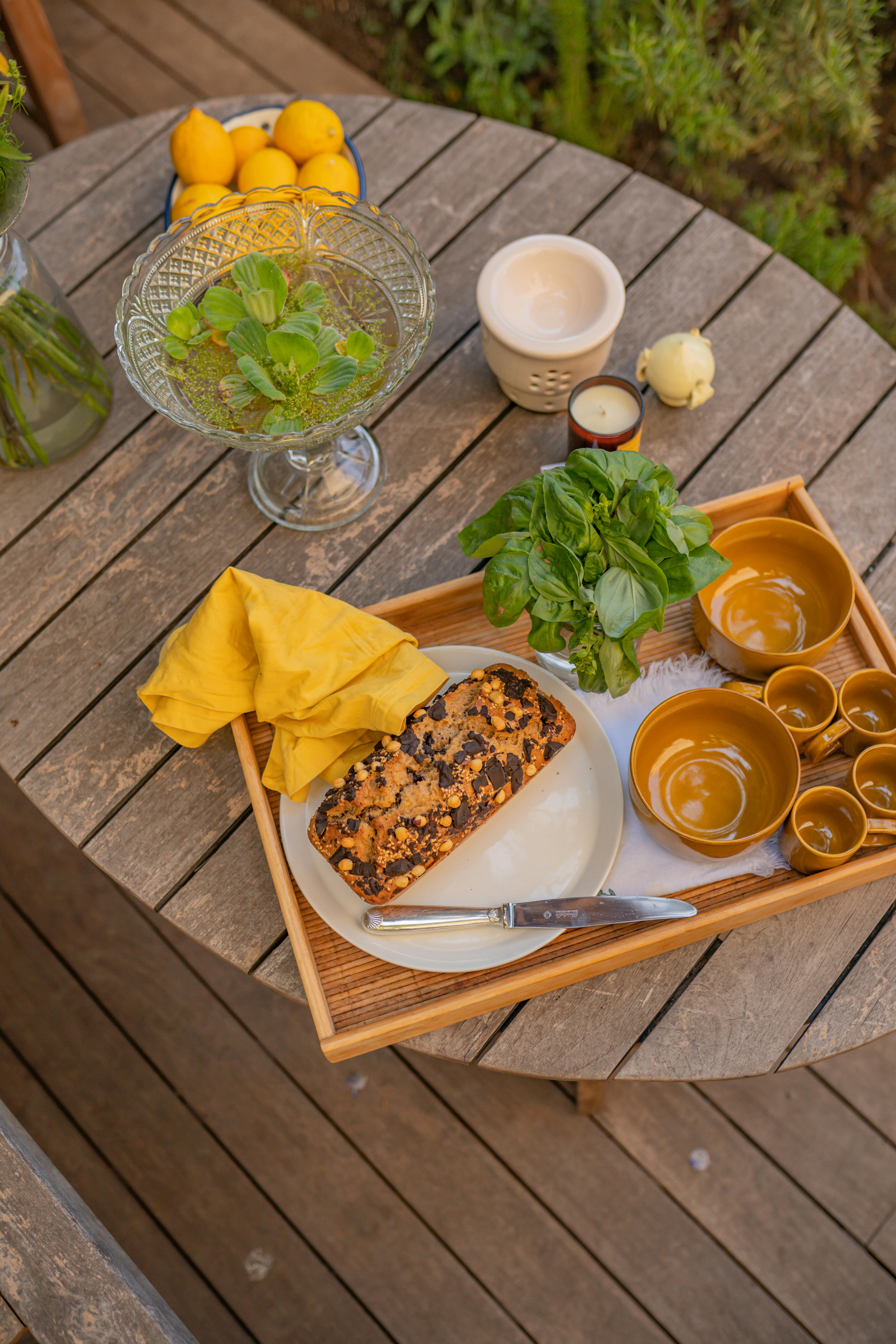 Overhead view of a rustic table with bread, herbs, and lemons, creating a calm outdoor dining atmosphere.