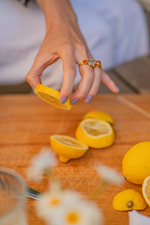 Close-Up Shot of a Person Holding a Sliced Lemon Fruit