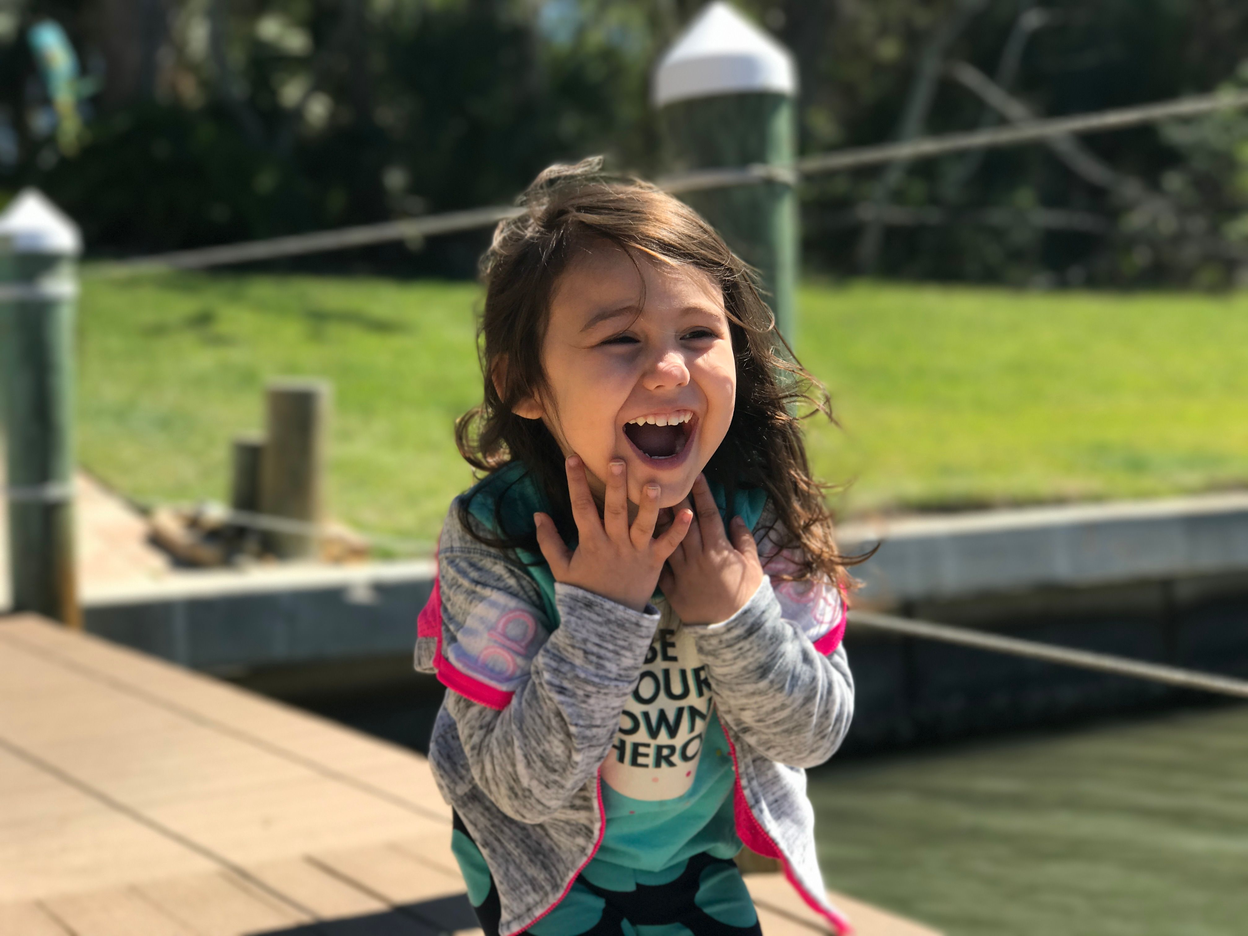 A child laughing joyfully on a sunny day at a waterfront in Palm Coast, FL.
