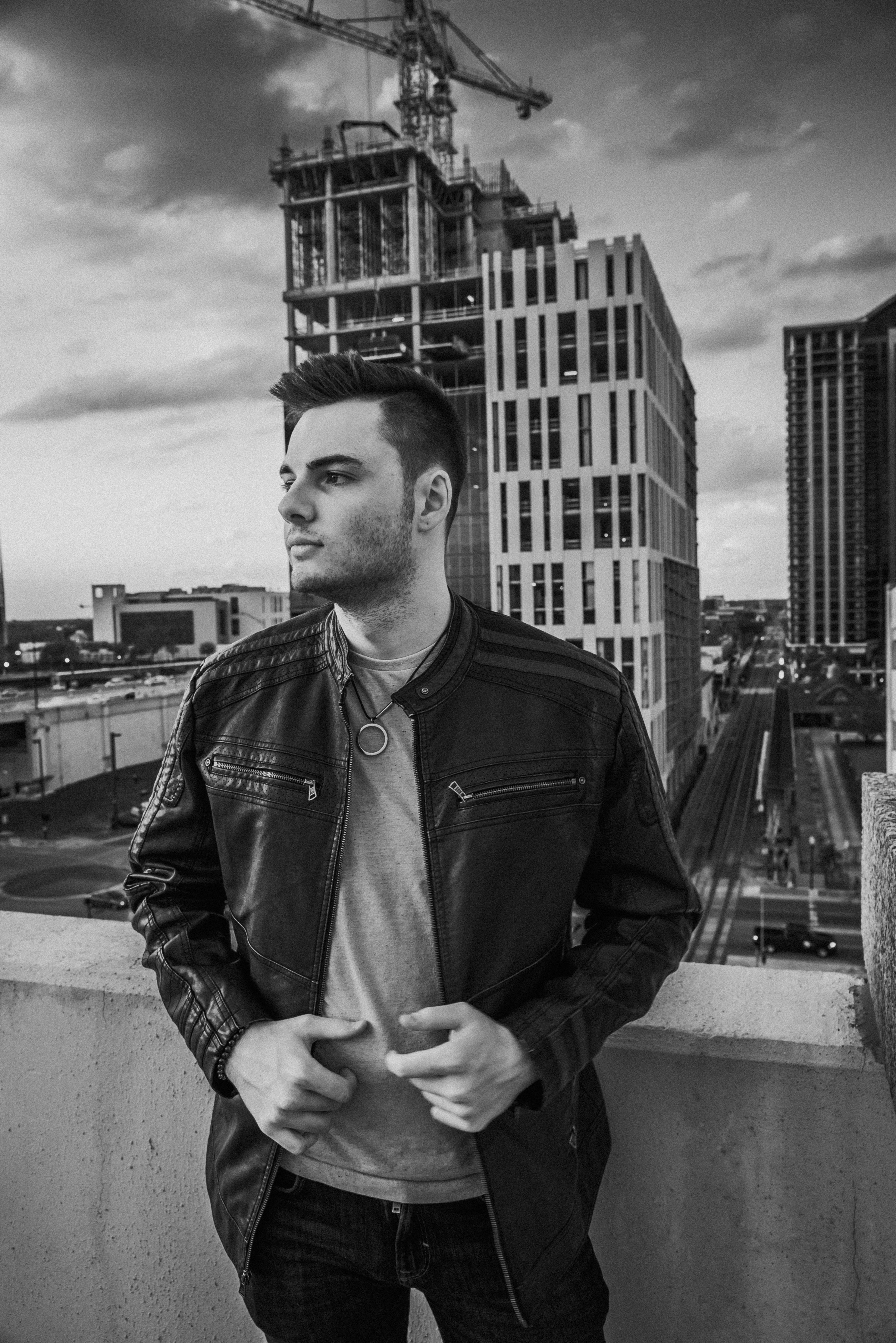 Black and white portrait of a man in urban setting with city skyline backdrop.