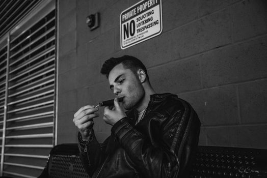 Photo of a Man Sitting on a Bench and Smoking