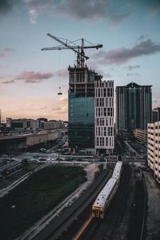 High-rise building under construction with a crane, set against a cityscape at sunset.