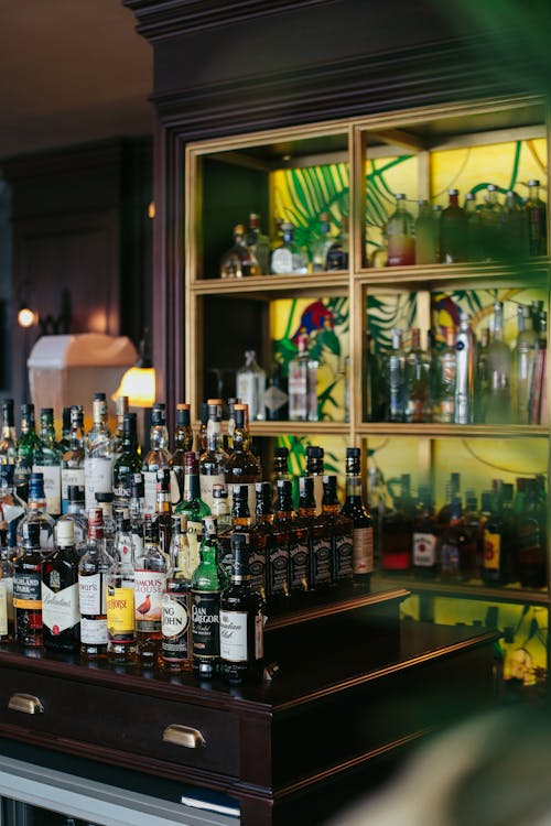 Bottles on Brown Wooden Shelves and Counter