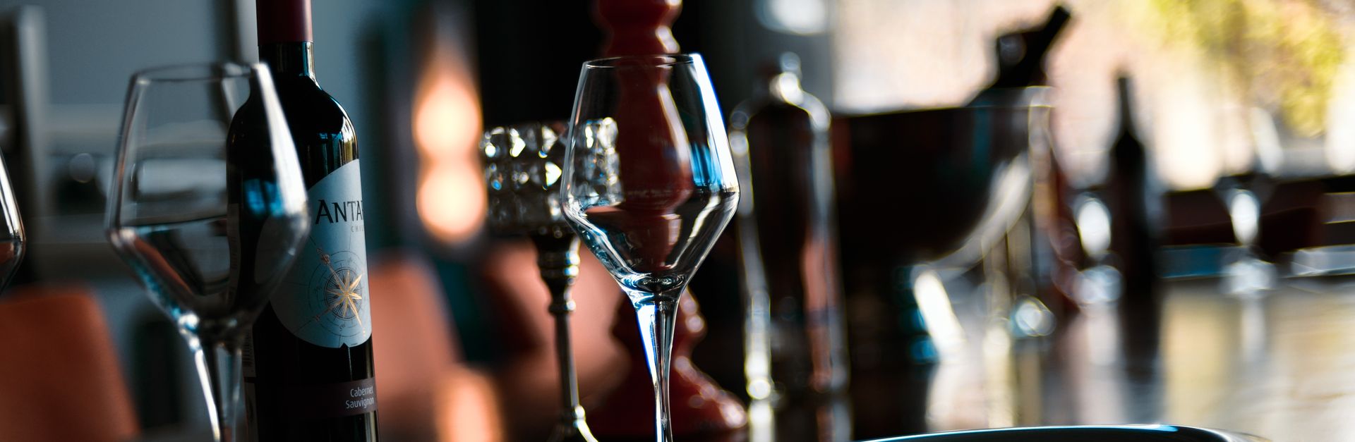 A sophisticated indoor wine setting with glasses, a bottle, and warm lighting.