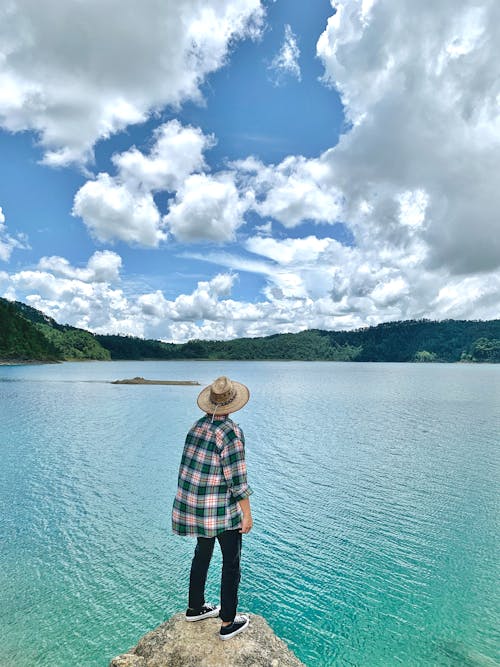 Person in Straw Hat Standing on Lake Shore