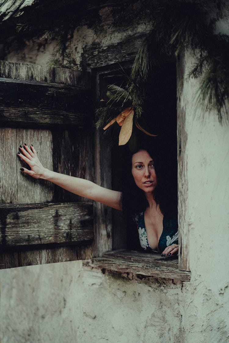 Woman Looking Out Of Wooden Window In Old House