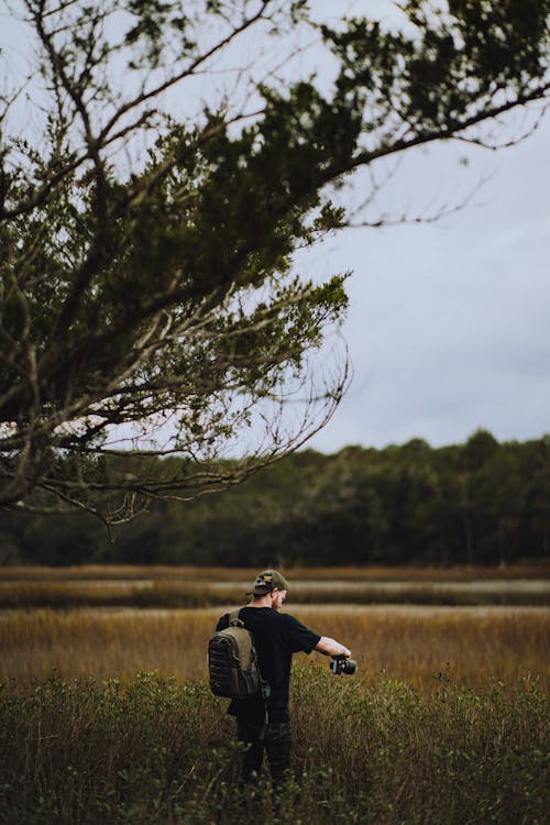 A Person in Black Shirt taking Pictures on Grass Field