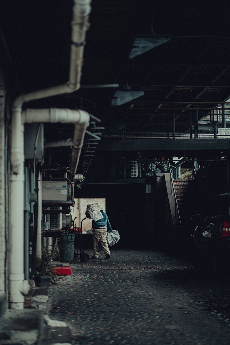 Man Carrying Load On Shoulders Inside An Industrial Plant