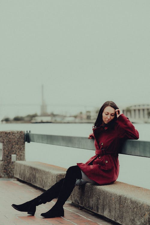 Brunette Woman in Red Coat Sitting on Bench