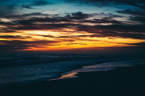 Free Stunning sunset over ocean waves with vibrant colors and dramatic clouds. Stock Photo