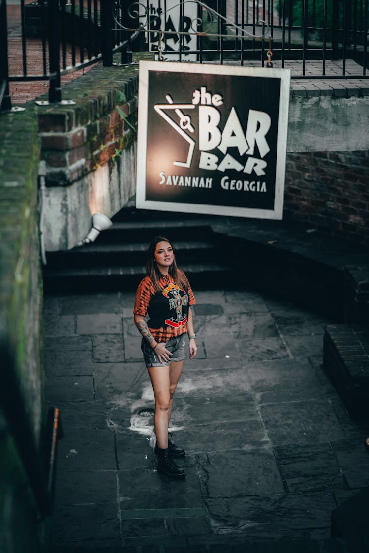 A Woman Standing Beside The Bar Signage