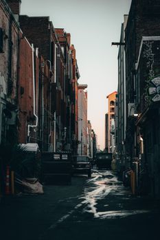 A dark, moody alleyway in the city showcases urban architecture and soft evening light.