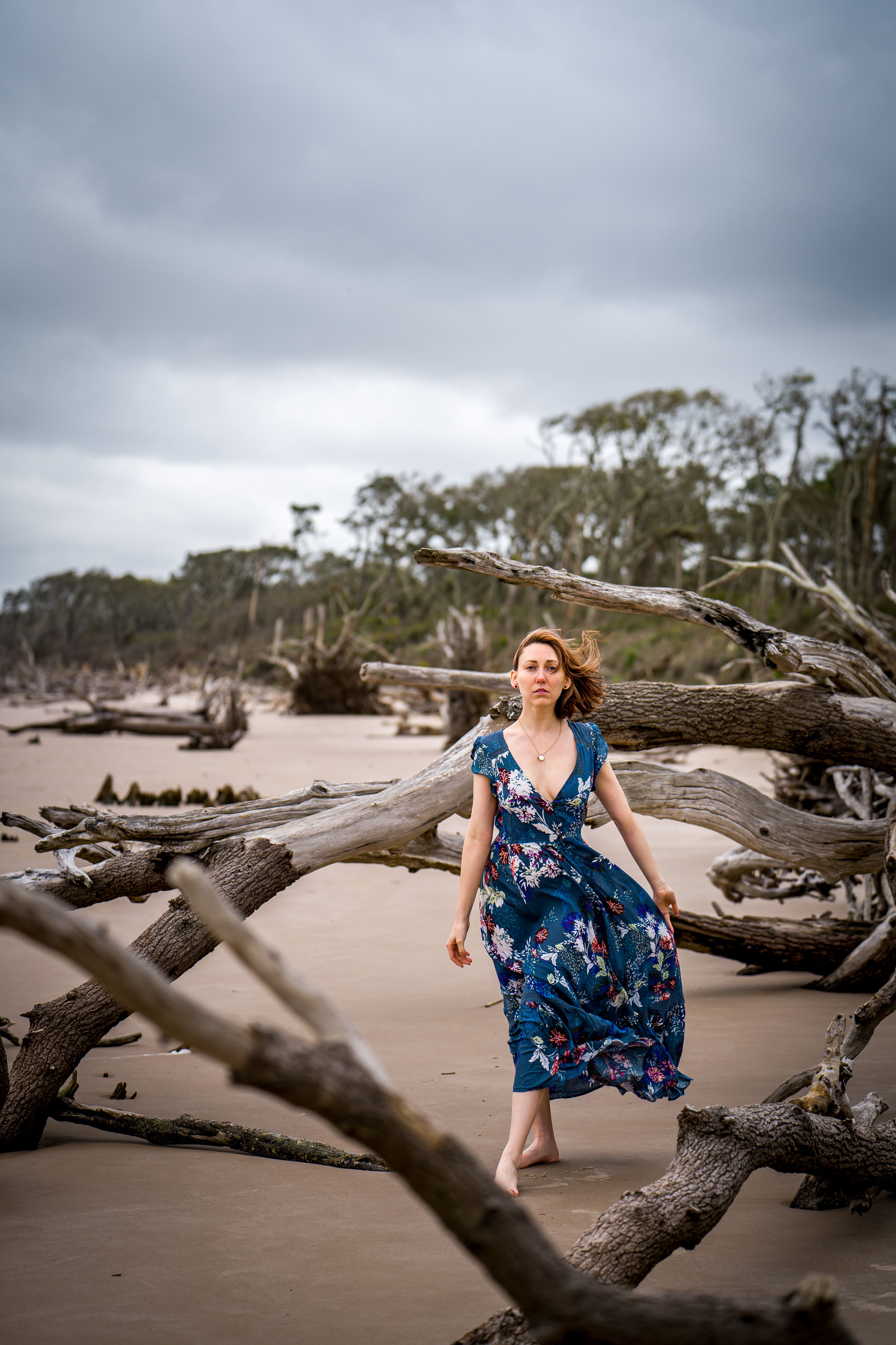 Woman in a Blue and White Floral Dress Walking on Sand · Free Stock Photo