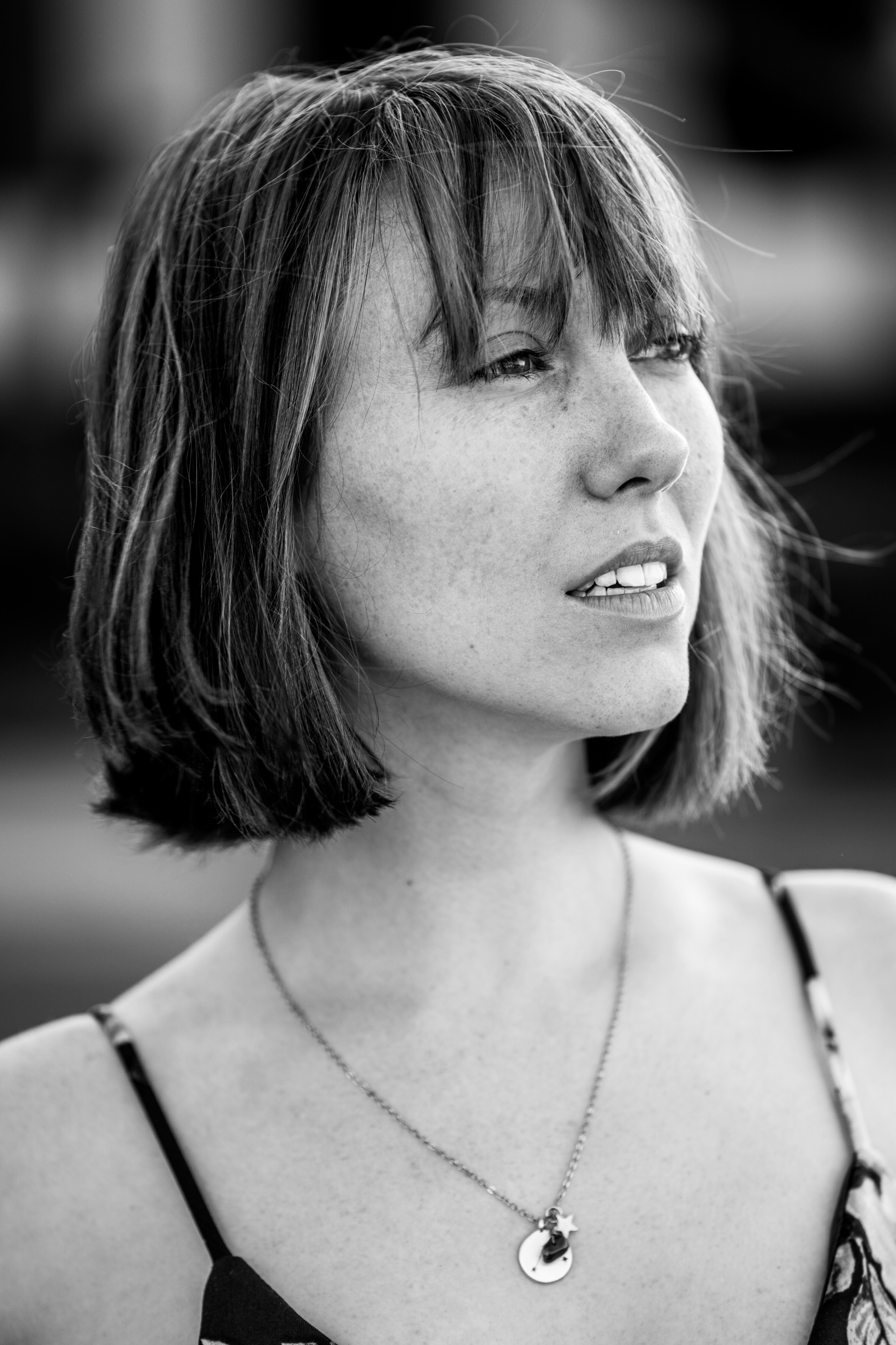 Elegant black and white portrait of a woman wearing a necklace and spaghetti strap top.