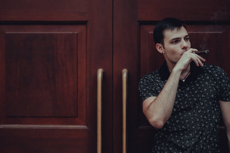 Man Smoking Cigar Standing By Door