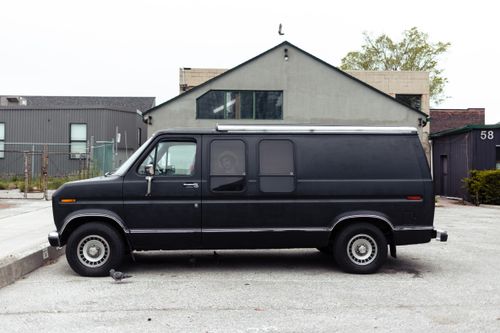Free A classic black van parked in an urban setting in Toronto, Canada, highlighting urban architecture. Stock Photo