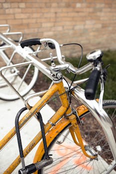 Retro yellow bicycle with rusty details parked against a brick wall, featuring selective focus.