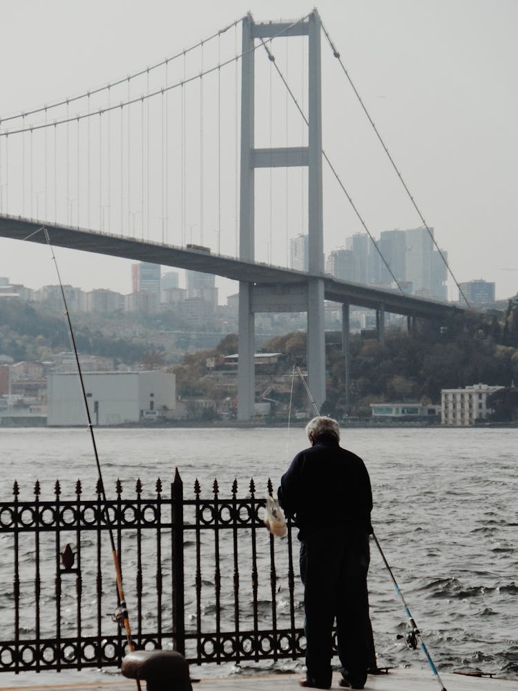 A Man Fishing From The Dock