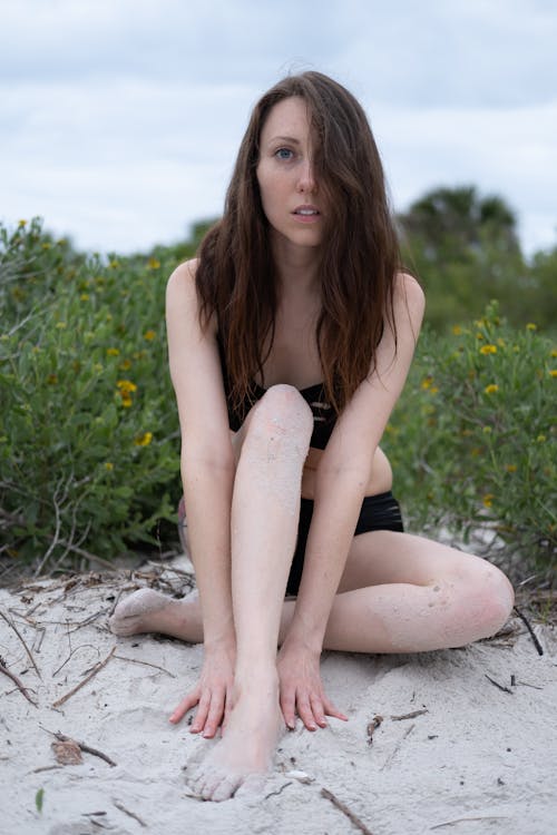 Sexy Woman Wearing Her Black Bikini while Sitting on Beach Sand