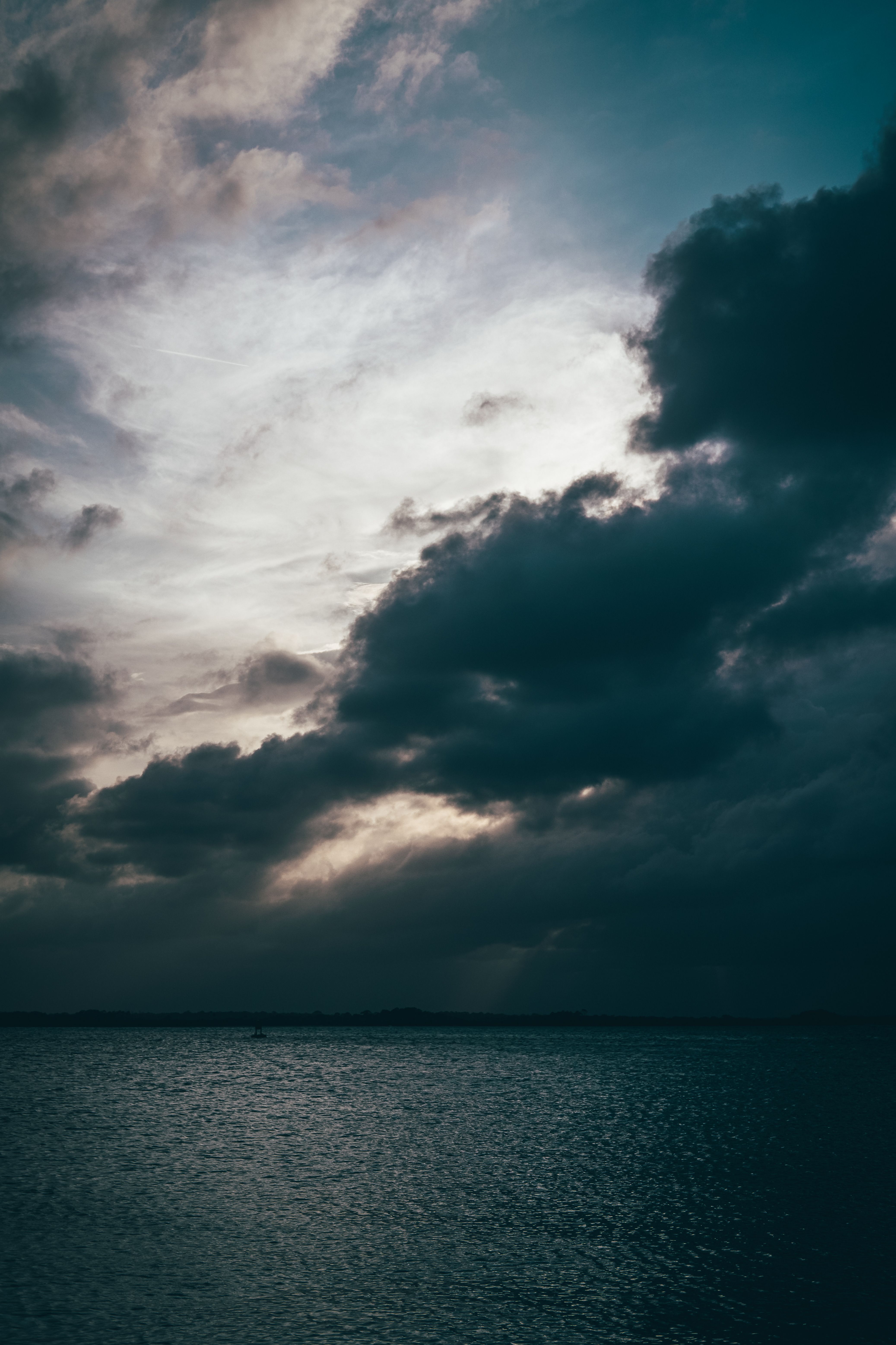 Dark, dramatic clouds over a calm sea at dusk — photo by Connor Scott McManus on Pexels