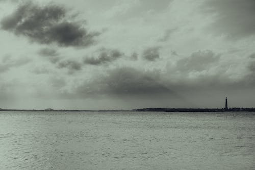 Grayscale Photo of Ocean under the Cloudy Sky