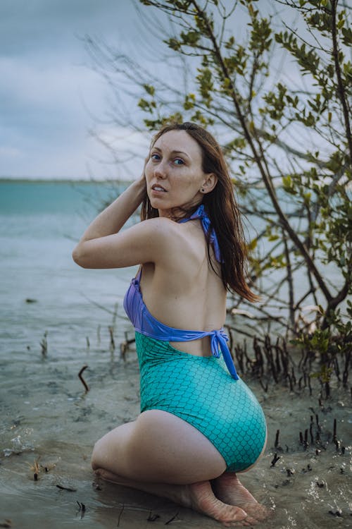 Woman in Purple and Green Bathing Suit Sitting on Beach