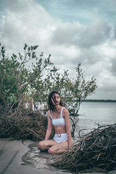 A woman in a white bikini enjoys a peaceful moment at a lush beach.