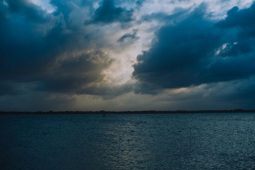 Free A serene and dramatic view of a cloudy sky over a calm ocean capturing the beauty of nature. Stock Photo