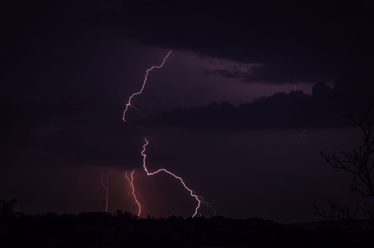 captivating lightning bolt illuminates a dark night sky above silhouet