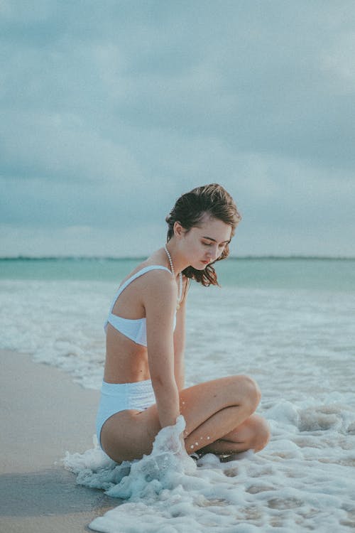 A Woman in White Bikini Sitting on White Sand