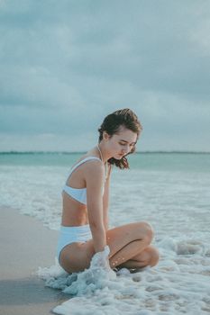 A peaceful scene of a woman enjoying summer by the sea in a white bikini.