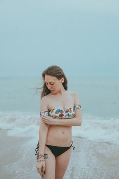 Young woman in a floral bikini enjoying a peaceful day at the beach, embodying relaxation and leisure.