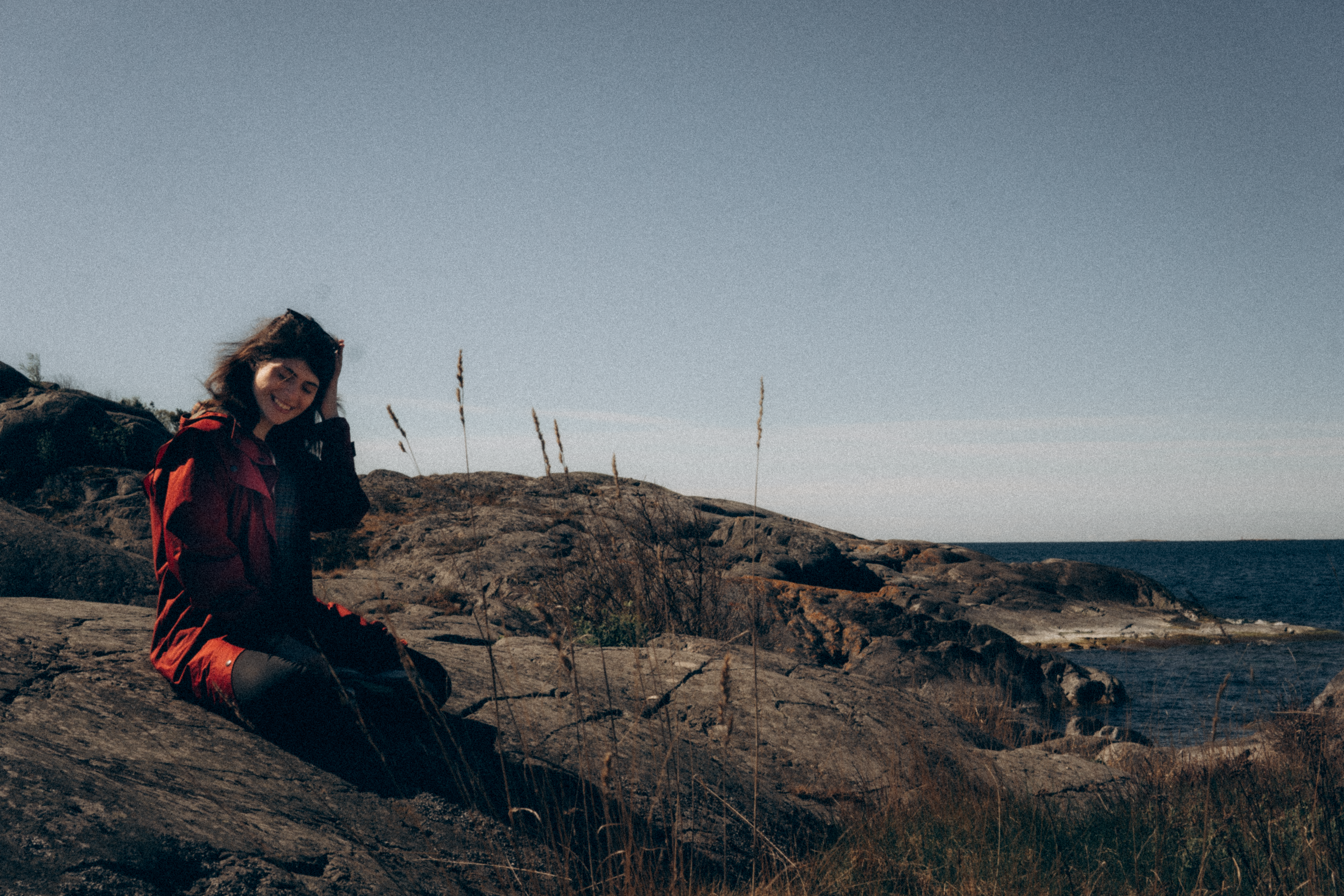 Woman in Black Jacket Sitting on Brown Rock Formation · Free Stock Photo
