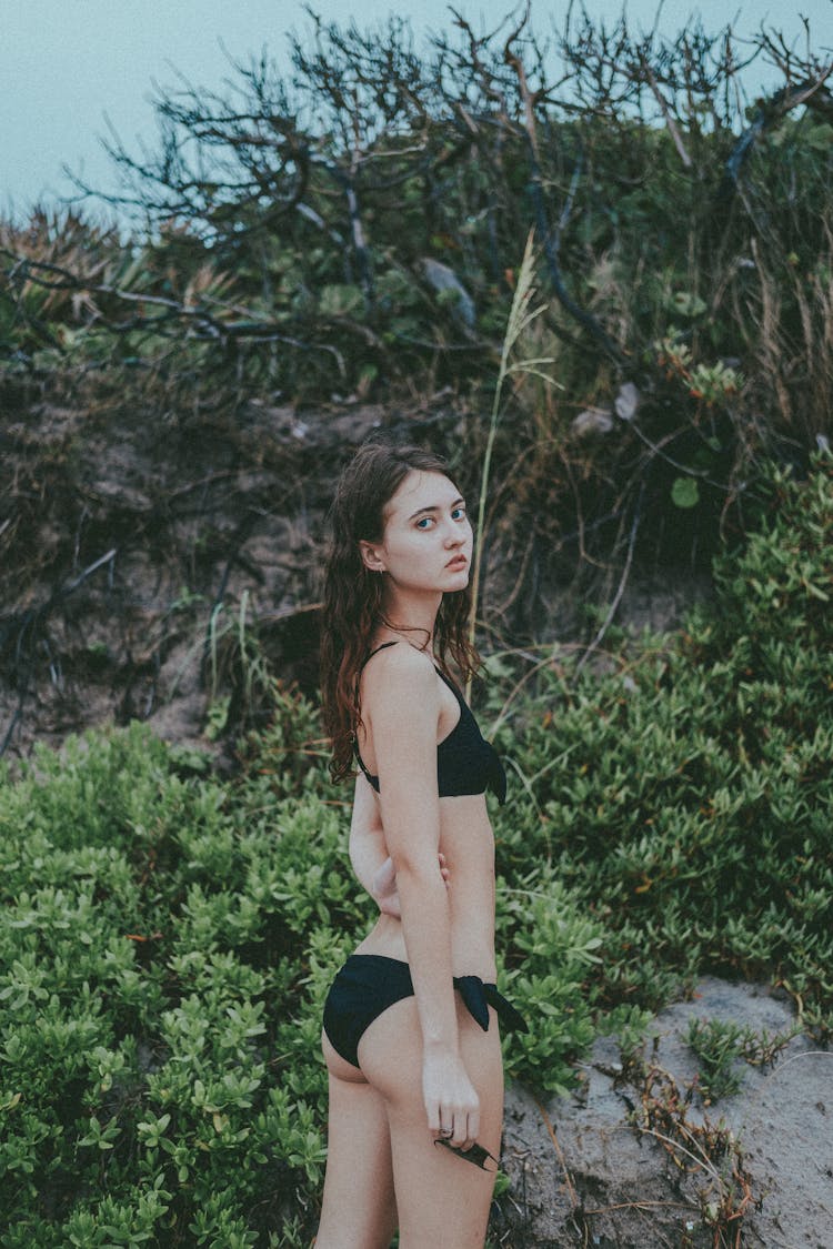 Woman In Black Swimwear Standing Near The Plants In The Beach